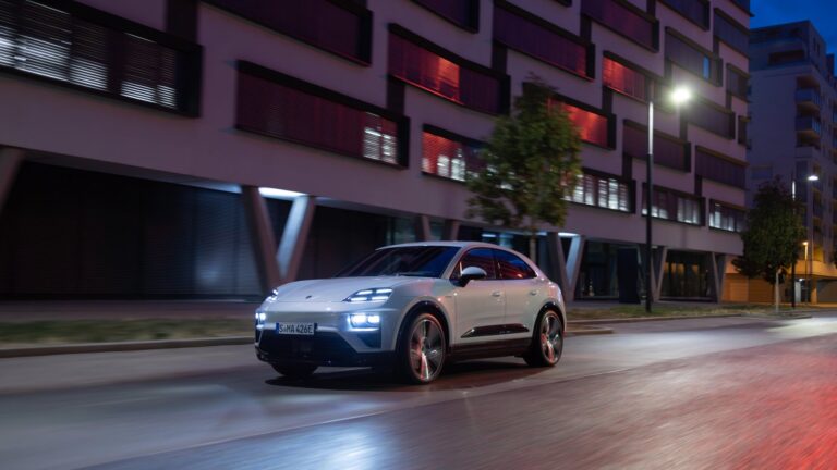 Porsche Macan drives down an empty urban street at night.