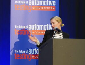 ATTI editor Rachel Evans speaking on stage at The Future Of Automotive Technology Conference in 2024, in front of a brand logo