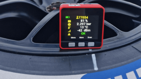 Bf1systems launches pocket-size instant TPMS diagnostic tool The Bf1systems 1System QuickScan diagnostic tool, with a red external metal case and a colour screen, attached to a motorsport vehicle wheel.